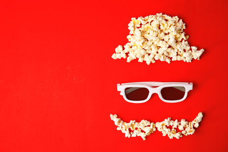 Face made of popcorn and glasses on color background, top view with space for text. cinema snackの写真素材