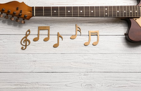 Music notes and guitar neck on wooden background, top view. Space for textの写真素材
