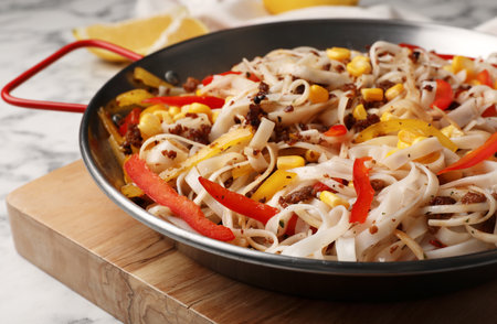 Frying pan with rice noodles, meat and vegetables on tableの写真素材