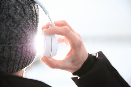 Young man listening to music with headphones outdoors, closeupの写真素材