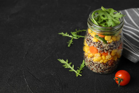 Jar with healthy quinoa salad and vegetables on table. Space for textの写真素材