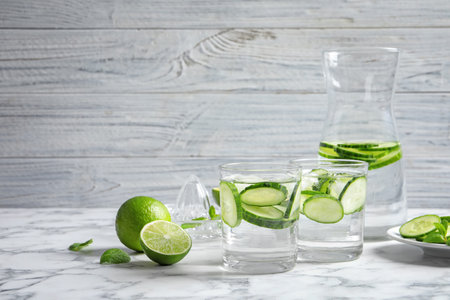 Glasses with fresh cucumber water on table against light background. Space for textの写真素材