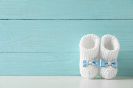 Handmade baby booties on table against wooden background. Space for textの写真素材