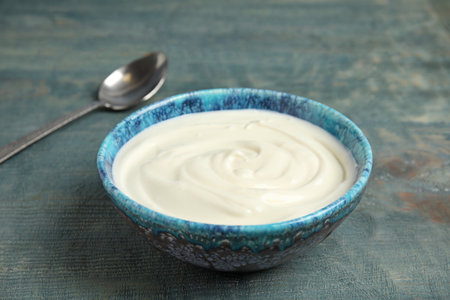 Bowl with creamy yogurt on blue wooden backgroundの写真素材