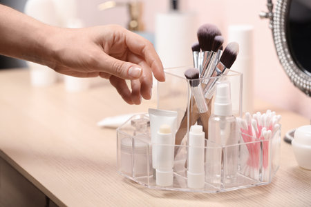 Woman taking cosmetic products from holder on dressing table, closeupの写真素材