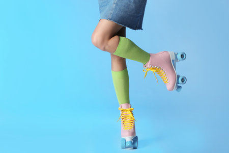 Woman with vintage roller skates on color background, closeup. Space for text