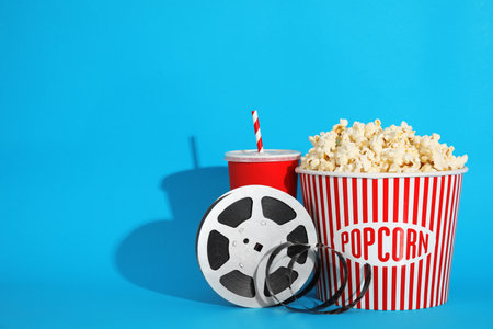Popcorn, reel and drink on color background, space for text. cinema snackの写真素材
