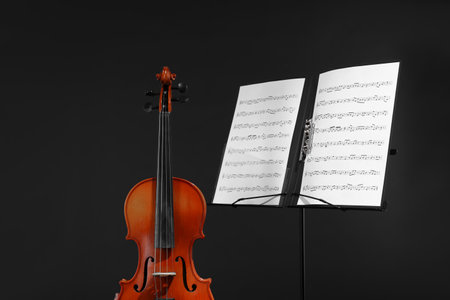 Violin and note stand with music sheets on black backgroundの写真素材