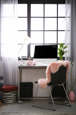 Stylish workplace with computer near window at home office. Space for textの写真素材