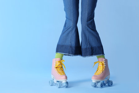 Woman with vintage roller skates on color background, closeup. Space for text