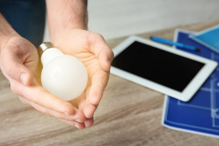 Man holding lamp over table, closeup with space for text