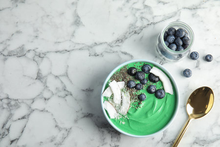 Bowl of spirulina smoothie and blueberries on marble background, top view with space for textの写真素材