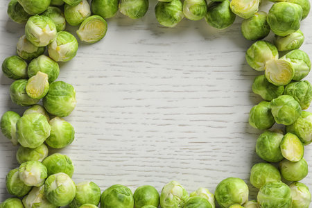 Frame made with Brussels sprouts on wooden background, top view. Space for textの写真素材