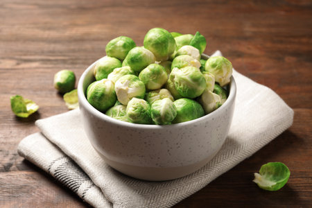 Bowl of fresh Brussels sprouts and napkin on wooden tableの写真素材