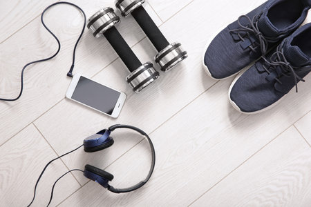 Flat lay composition with sneakers, headphones, mobile phone and dumbbells on wooden backgroundの写真素材