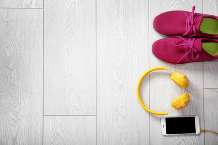 Flat lay composition with sneakers, headphones and mobile phone on wooden background. Space for textの写真素材