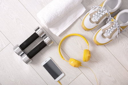 Flat lay composition with sneakers, headphones, mobile phone, towel and dumbbells on wooden backgroundの写真素材