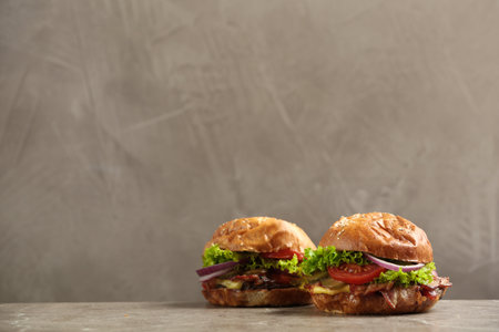 Delicious burgers with bacon on table against gray background. Space for textの写真素材