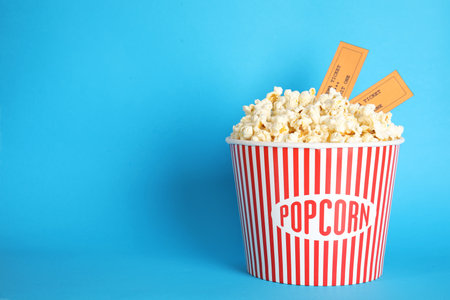 Bucket of fresh tasty popcorn and tickets on color background, space for text. cinema snackの写真素材