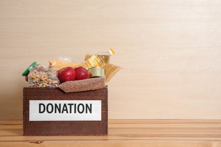 Donation box with food on table against light background. Space for textの写真素材