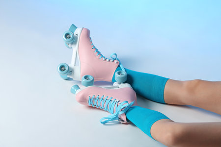 Woman with vintage roller skates on color background, closeup