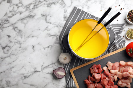 Flat lay composition with fondue pot, raw meat and space for text on marble backgroundの写真素材