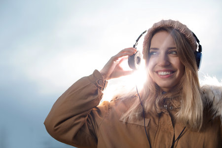 Young woman with headphones listening to music outdoors. Space for textの写真素材
