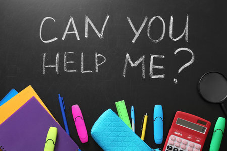 Flat lay composition with school supplies and phrase "Can you help me?" on chalkboardの写真素材