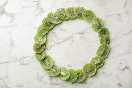 Frame made of kiwi on marble background, top view with space for text. Dried fruit as healthy foodの写真素材