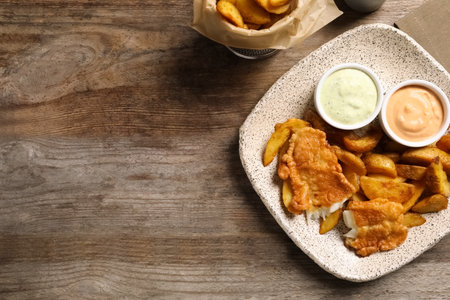 Plate with British traditional fish and potato chips on wooden background, top view. Space for textの写真素材