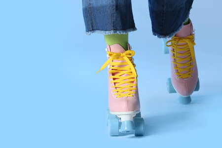 Woman with vintage roller skates on color background, closeup. Space for text