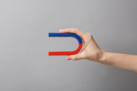 Woman holding magnet on gray background, closeup. Space for textの写真素材