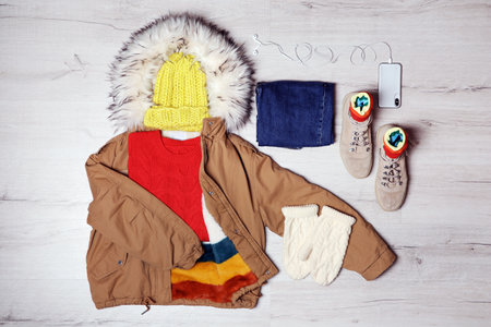 Set of warm clothes and mobile phone on wooden background, flat lay. winter holidaysの写真素材