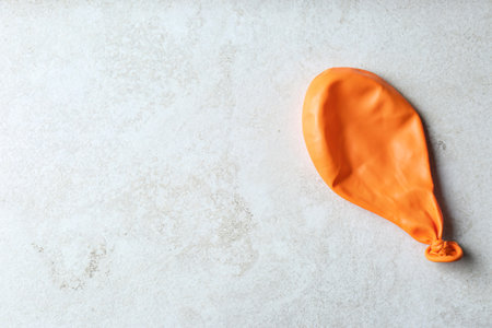 Orange deflated balloon on gray background, top view with space for textの写真素材
