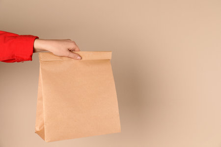 Woman holding paper bag on color background. Mockup for designの写真素材