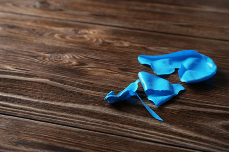 Popped balloon on wooden background, space for textの写真素材