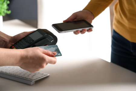 Women using modern payment terminal at table indoors, closeupの写真素材