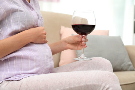 Future mother with glass of wine at home, closeup. Alcohol abuse during pregnancyの写真素材