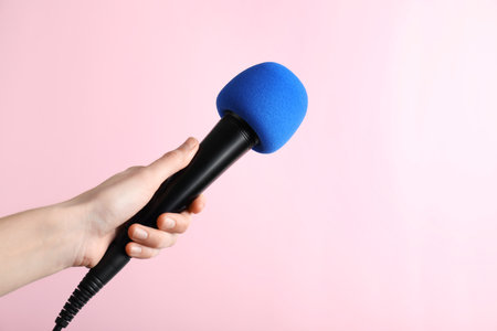 Woman holding microphone on color background, space for textの写真素材