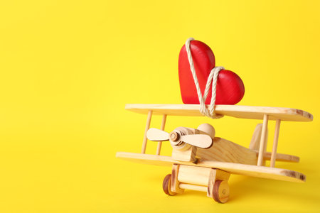 Small wooden airplane with heart on color background, space for textの写真素材