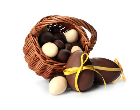 Wicker basket with sweet chocolate Easter eggs on white backgroundの写真素材
