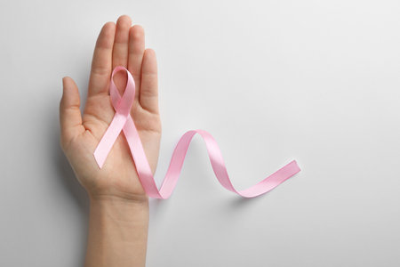 Woman holding pink ribbon on white background, top view with space for text. breast cancer awareness conceptの写真素材