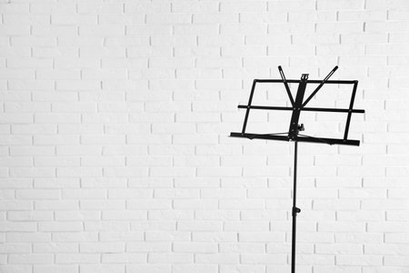 Empty music note stand near brick wall. Space for textの写真素材