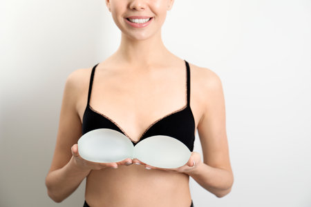 Woman holding silicone implants for breast augmentation on white background, closeup. cosmetic surgeryの写真素材