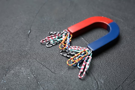 Magnet attracting paper clips on gray background, space for text
