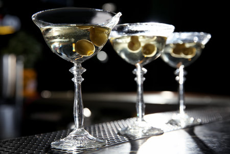 Glasses of martini cocktail with olives on bar counter. Space for textの写真素材