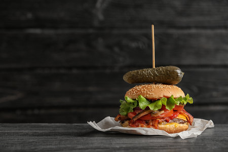 Tasty burger with bacon on wooden table. Space for textの写真素材
