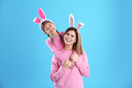 Happy woman and daughter with bunny ears on color backgroundの写真素材