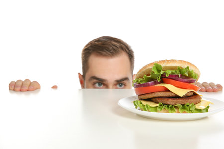 Young man with tasty burger on white backgroundの写真素材