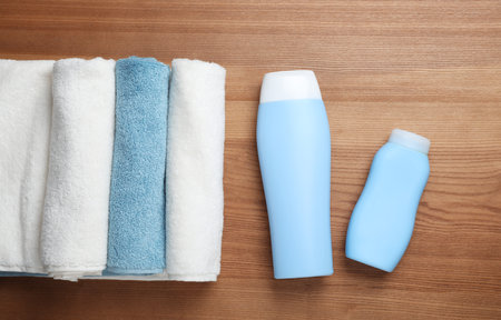 Bottles of shampoo and rolled towels on wooden background, top viewの写真素材